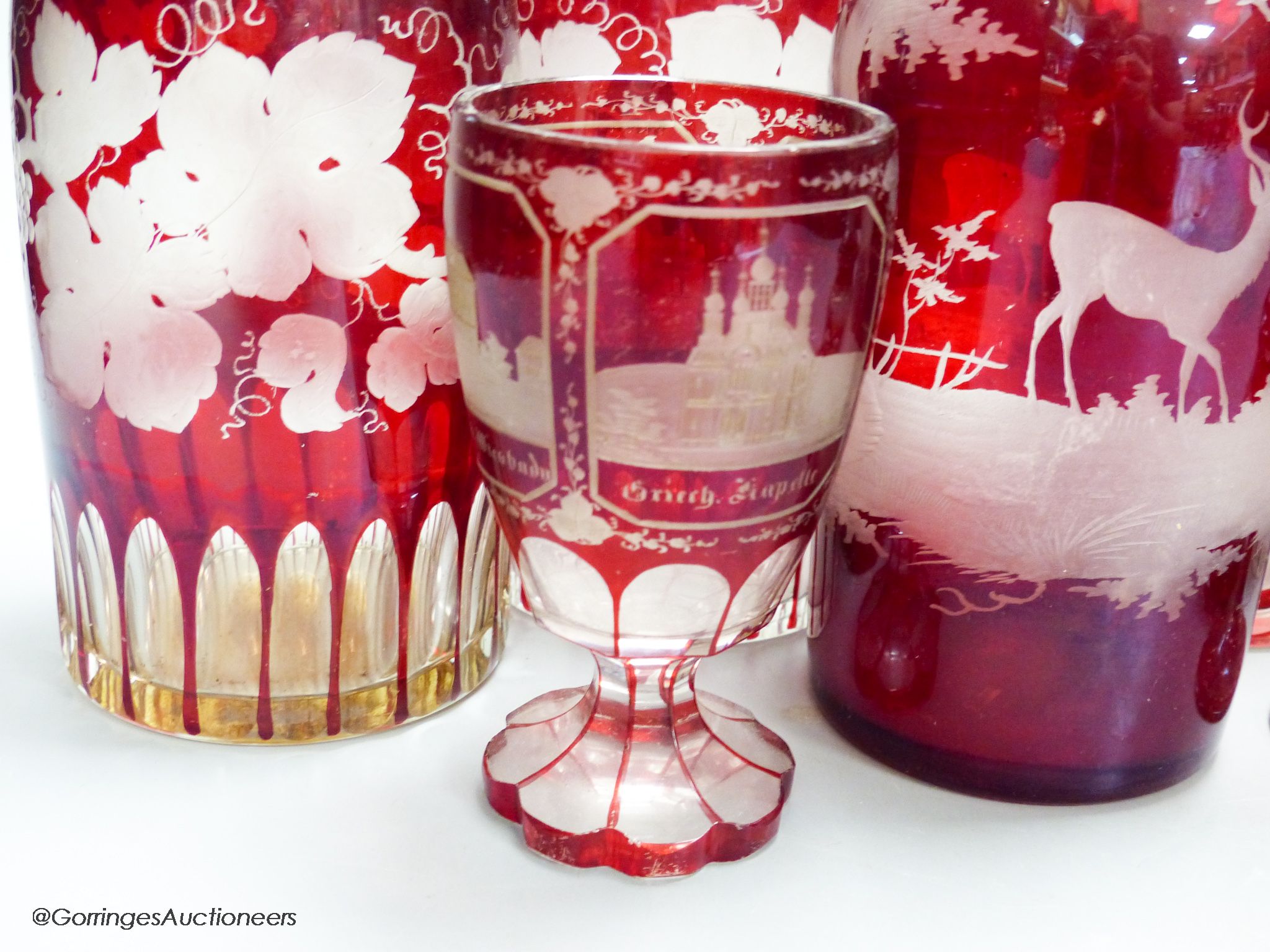 A collection of six Bohemian ruby flashed wheel engraved glass decanters, tallest 40cm, a similar spa beaker and liqueur glass